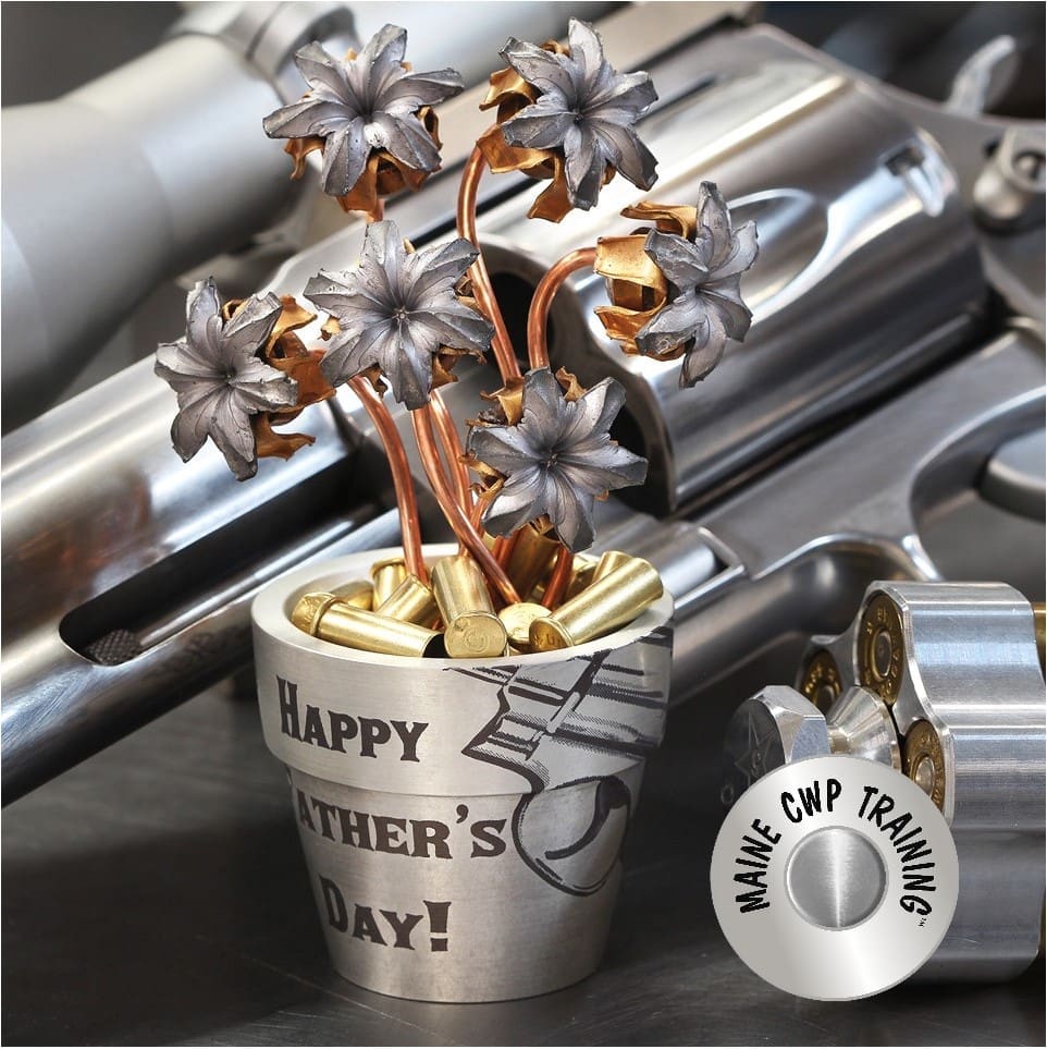 A metal cup with flowers in it sitting on top of a table.